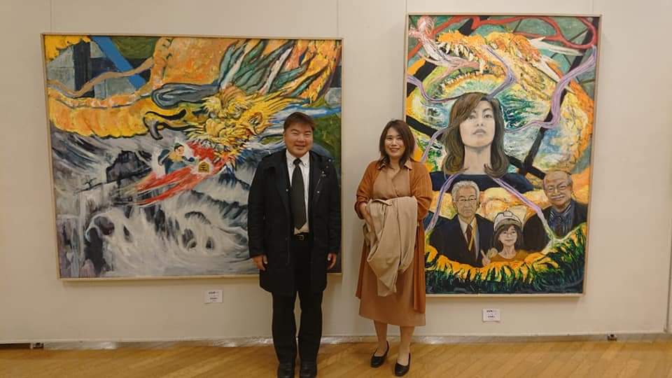 榊原平と画家の宮地靖江さんが絵の前で立って並んでいる様子