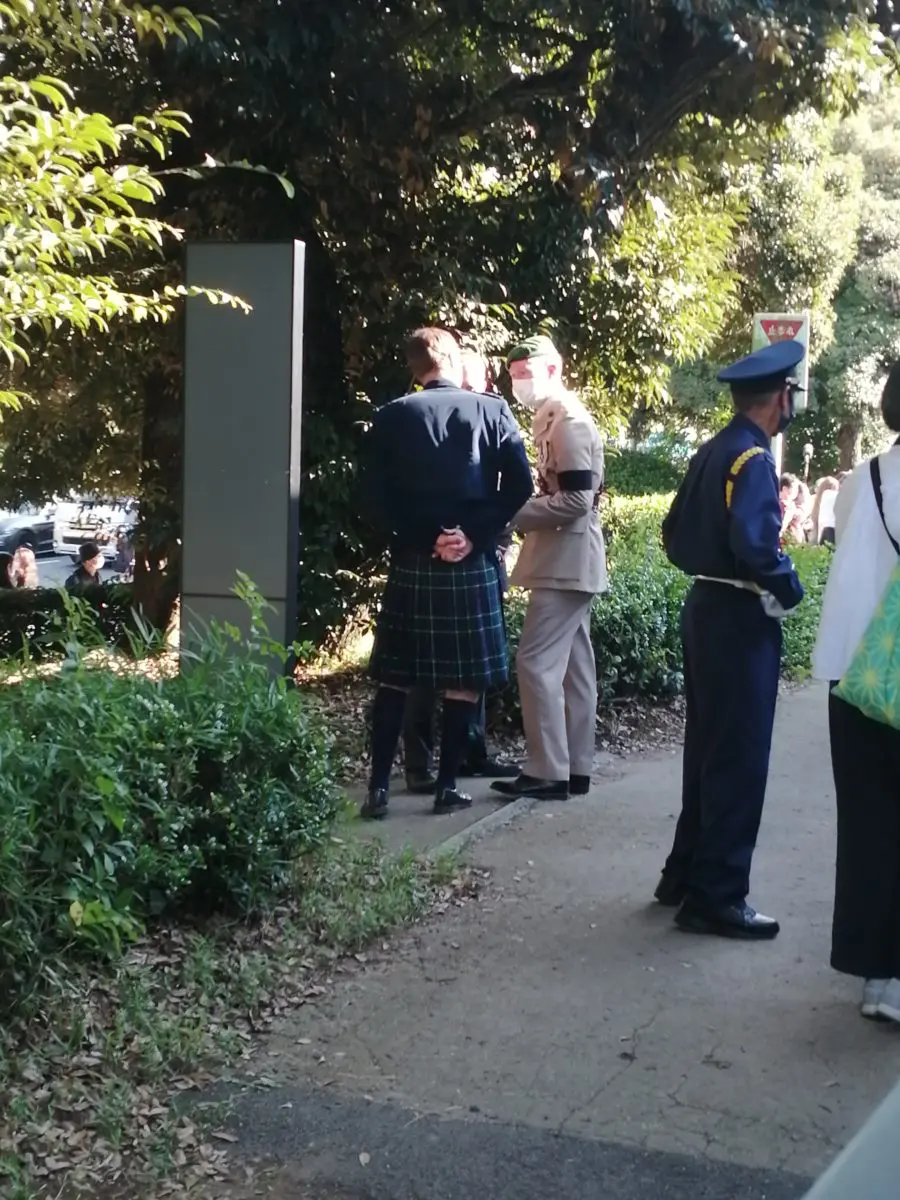 キルトを着用した男性と制服の男性が話している様子