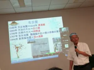 名古屋大学名誉教授 福和伸夫氏が、名古屋の歴史的災害を示すスライドを前に説明している。