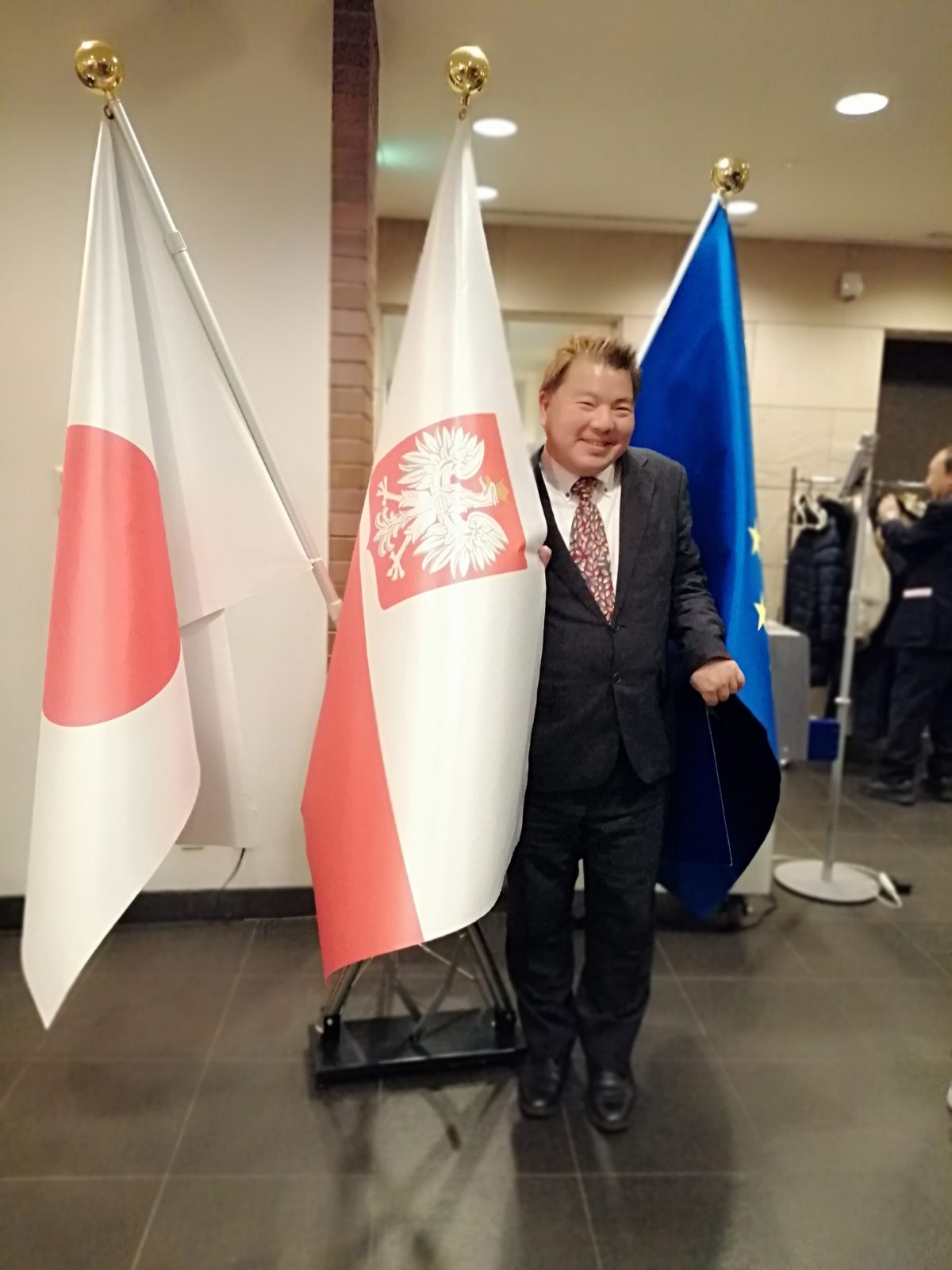 ポーランド国旗の前に立つ榊原平