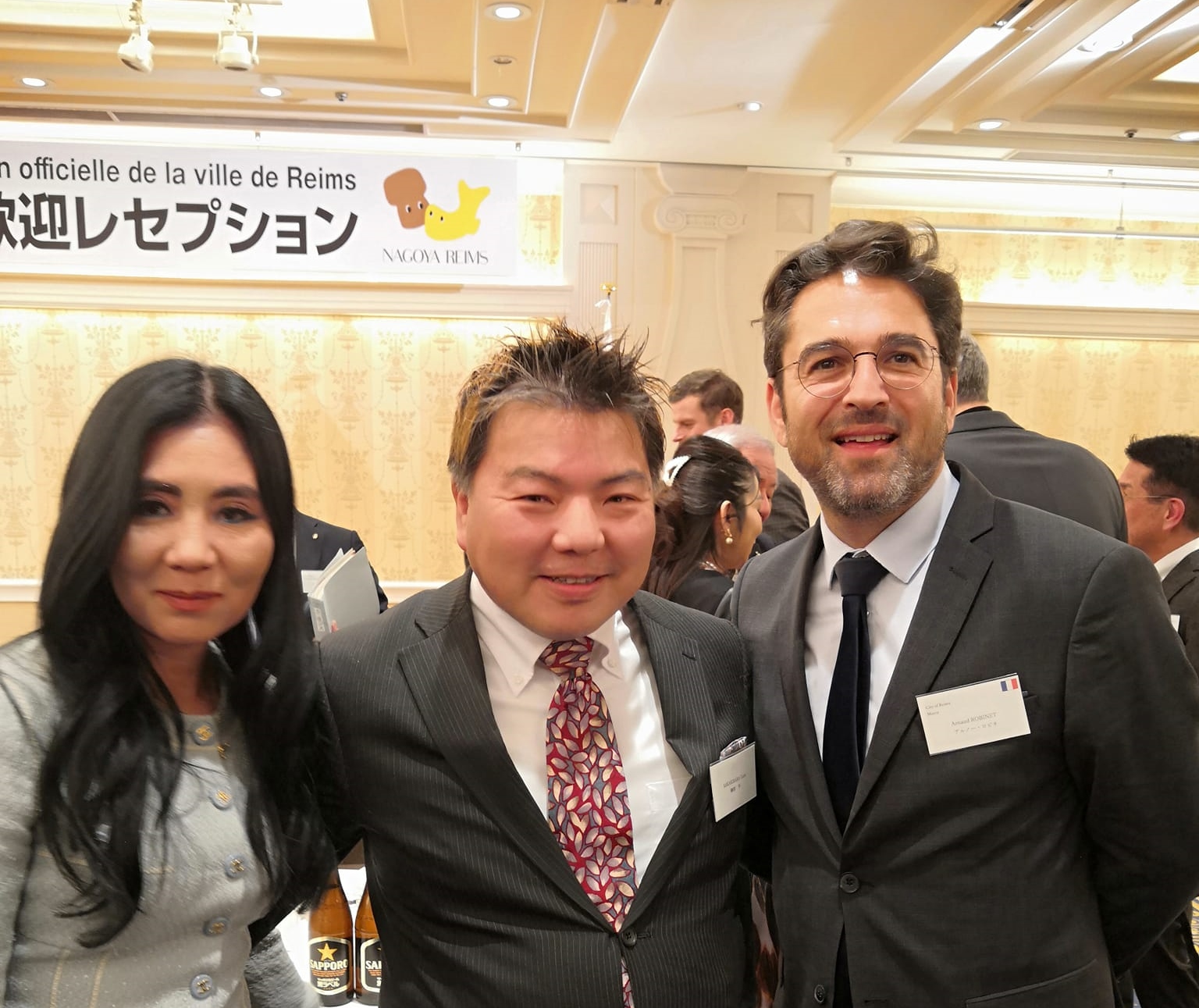 名古屋観光ホテルの宴会場に立つ３人、榊原平、フランス・ランス市長アルノー・ロビネ、深谷麻奈