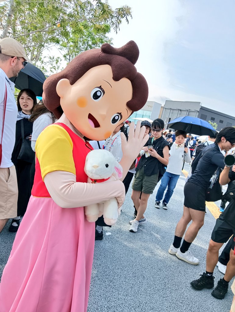 大阪・関西万博スイスパビリオン前に立つハイジの着ぐるみとユキちゃんのぬいぐるみ。ハイジが手を振っている。