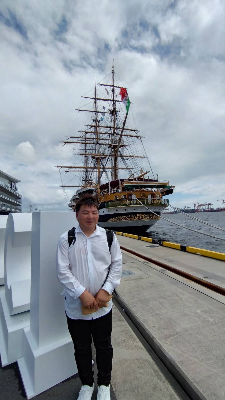 東京国際クルーズターミナルにて、アメリゴ・ヴェスプッチを背景に立つ榊原平。