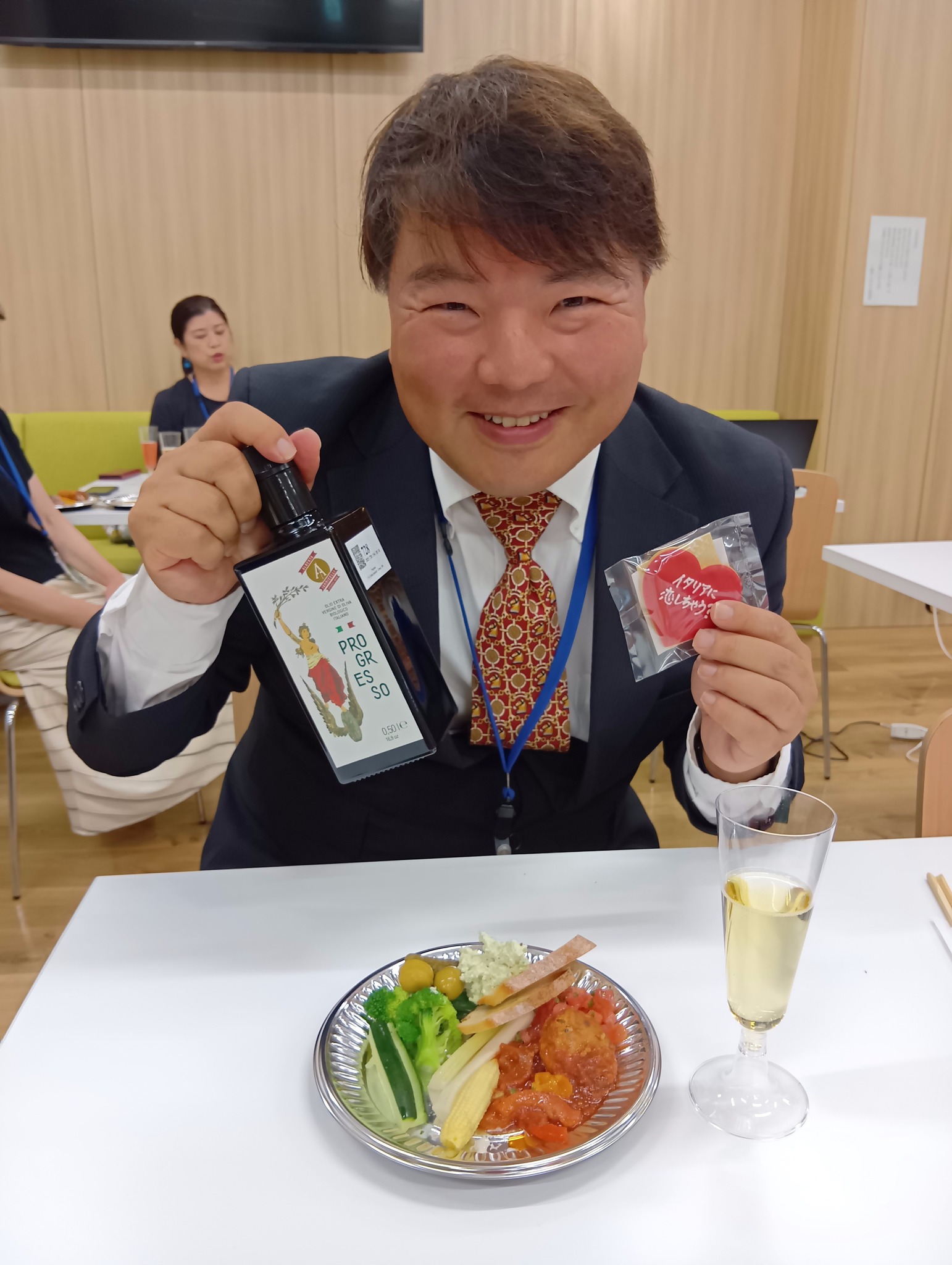 名古屋日伊協会 アペリティーボ 万博 富井貴子氏と語る2025年大阪・関西万博イタリア館の魅力 11 名古屋日伊協会 アペリティーボのイベントで、榊原平がオリーブオイルとハート型のクッキーを持って笑顔でいる写真。