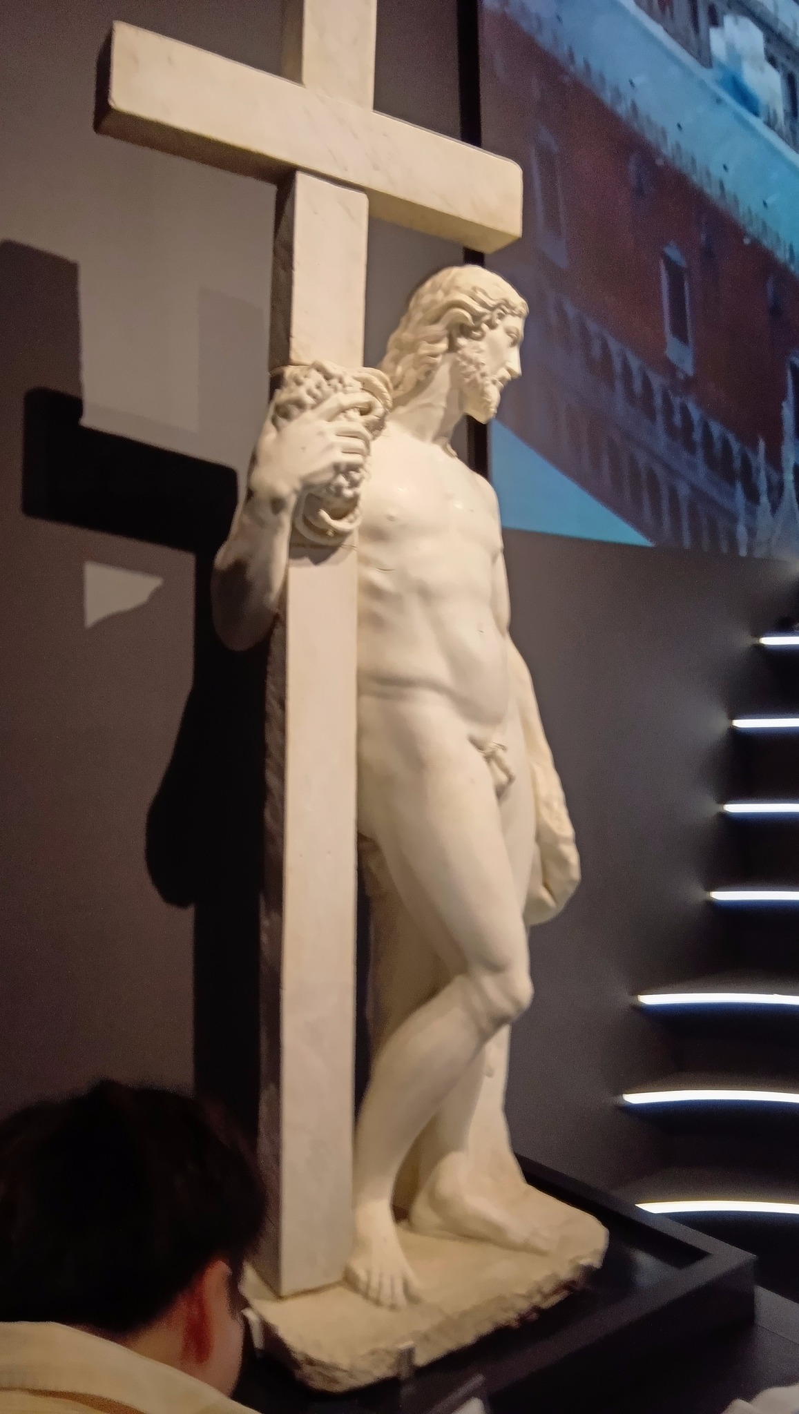 十字架にもたれかかるイエス・キリストの白い大理石像。ローマのサンタ・マリア・ソープラ・ミネルヴァ教会にあるミケランジェロ作の「十字架を担うキリスト」を彷彿とさせる。