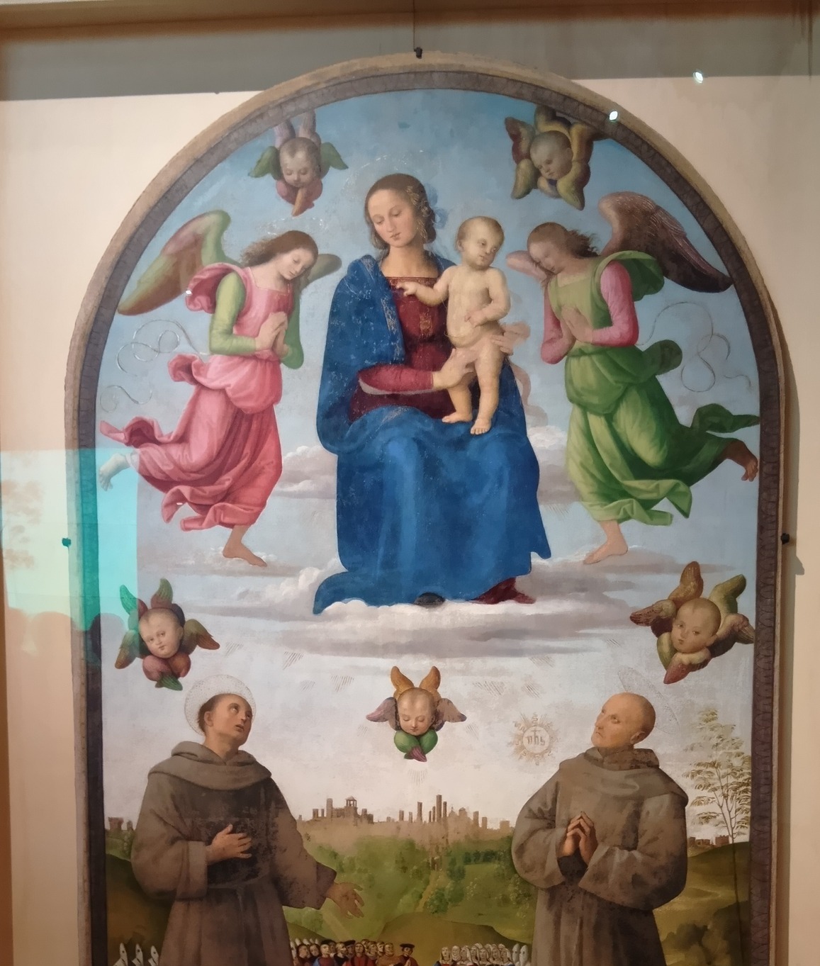 ウンブリア州ペルージャの画家ペルジーノによる祭壇画。中央に聖母子、その両脇を天使が囲み、下部に二人の聖人と人々が描かれている。