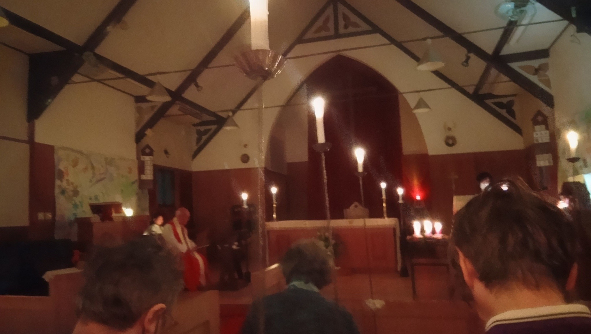 名古屋 聖マルコ教会から巡る2つの聖夜。心揺さぶる「かけがえのない命」に出会った布池教会への巡礼記録 2 名古屋聖マルコ教会の聖堂内部。多くのキャンドルが灯り、赤い祭服をまとった司祭が静かに座っている